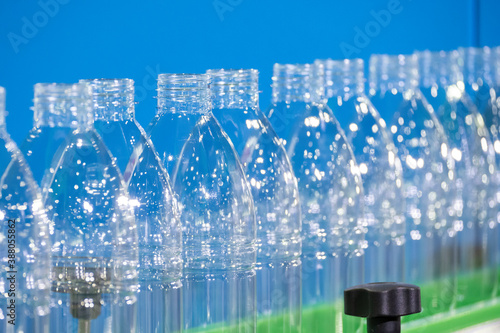 The PET bottles on the conveyor belt for filling process in the drinking water factory. The hi-technology of plastic bottle manufacturing process.