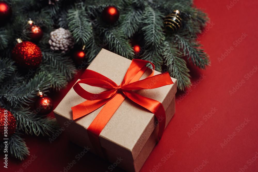 Gift box with red bow and Christmas tree twig on red background. Flat lay style. Christmas or New Year celebration concept Gift box with red bow and Christmas tree twig on red background. Flat lay style. Christmas or New Year celebration concept