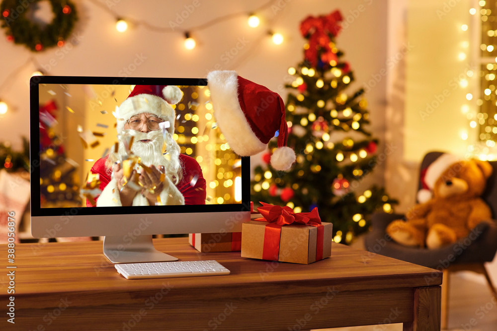 Computer on desk with Santa on screen blowing confetti and wishing Merry Xmas and Happy New Year