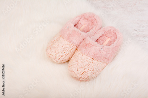 Pair of warm female slippers on white furry carpet
