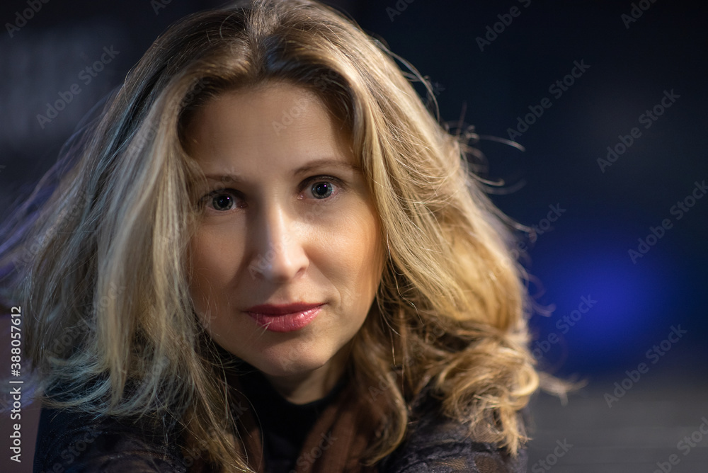 Close-up portrait of a young beautiful blonde woman with gray-green eyes on a dark background. Close-up portrait of a young beautiful blonde woman with gray-green eyes on a dark background.