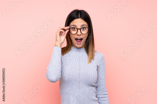 Woman over isolated pink background with glasses and surprised photo