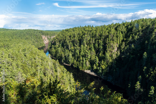A view looking out over the river and lush green forest of the Barron Canyon in eastern Algonquin Park, Ontario on a beautiful late summer day with a blue sky. photo