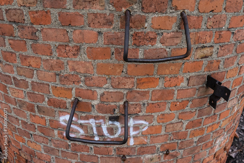 large metal staples in a brick wall. ladder on a large pipe and the inscription Stop