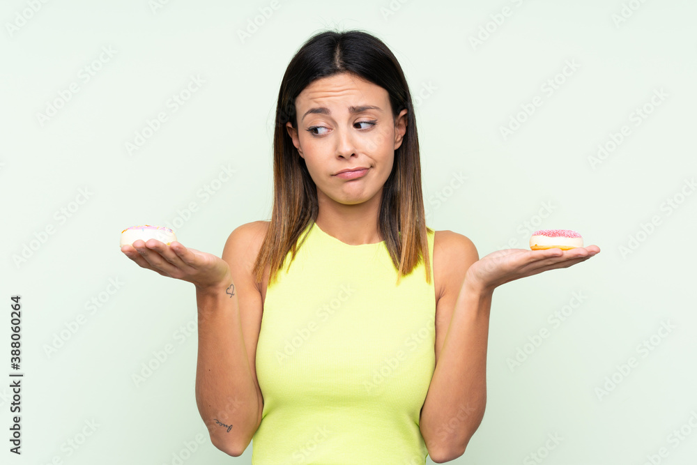Woman over isolated green background holding donuts Woman over isolated green background holding donuts