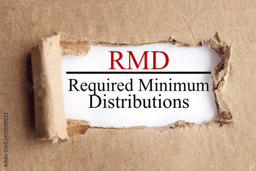 RMD Required Minimum Distribution .text on white paper on torn paper background