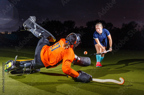 Young field hockey player attacks the goalkeeper photo