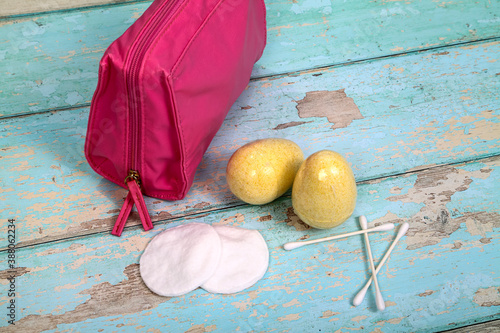Make up bag with cotton swabs pads and bath fizzers on a rustic wooden background photo
