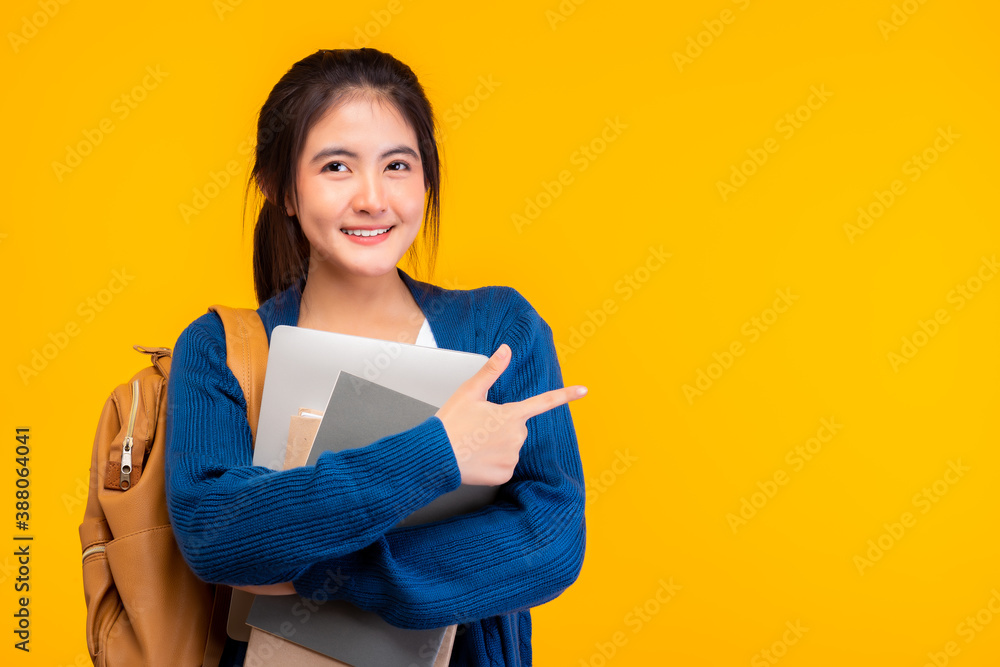 Happy asian female college student smiling at camera on yellow ...