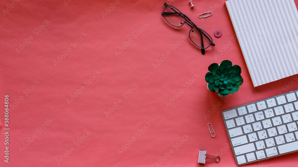 Styled stock photography pink office desk table with blank notebook, keyboard, cactus, macaroon, supplies and glasses. Top view with copy space. Flat lay.