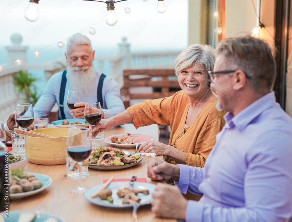 Cheerful senior friends enjoy dinner together on patio at home - Food and drink Cheerful senior friends enjoy dinner together on patio at home - Food and drink