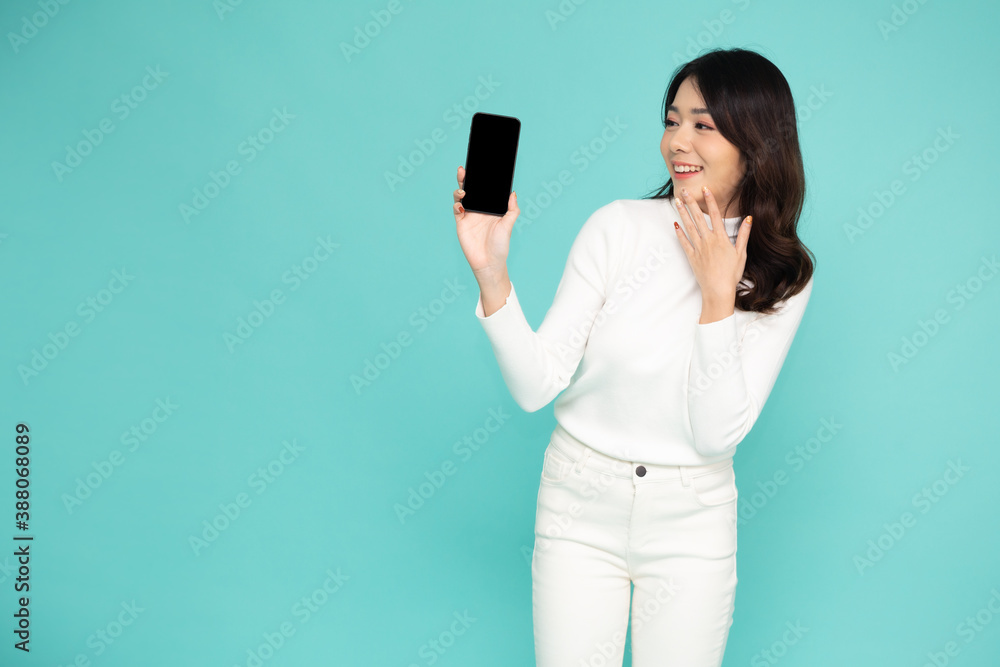 Portrait of beautiful Asian woman showing or presenting mobile phone application on hand isolated over light green background Portrait of beautiful Asian woman showing or presenting mobile phone application on hand isolated over light green background