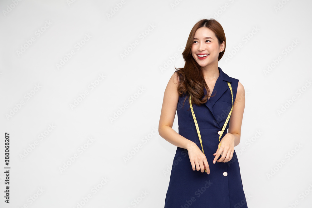 Portrait of a woman fashion designer clothes in deep blue dress with measuring tape isolated over white background, Asian female stylish model
