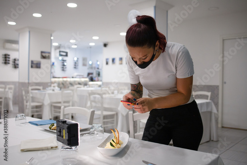 Young owner of the restaurant takes the picture of the dish prepared by the shef. concept do communication with customers through social networks. Tell customers about the new dishes