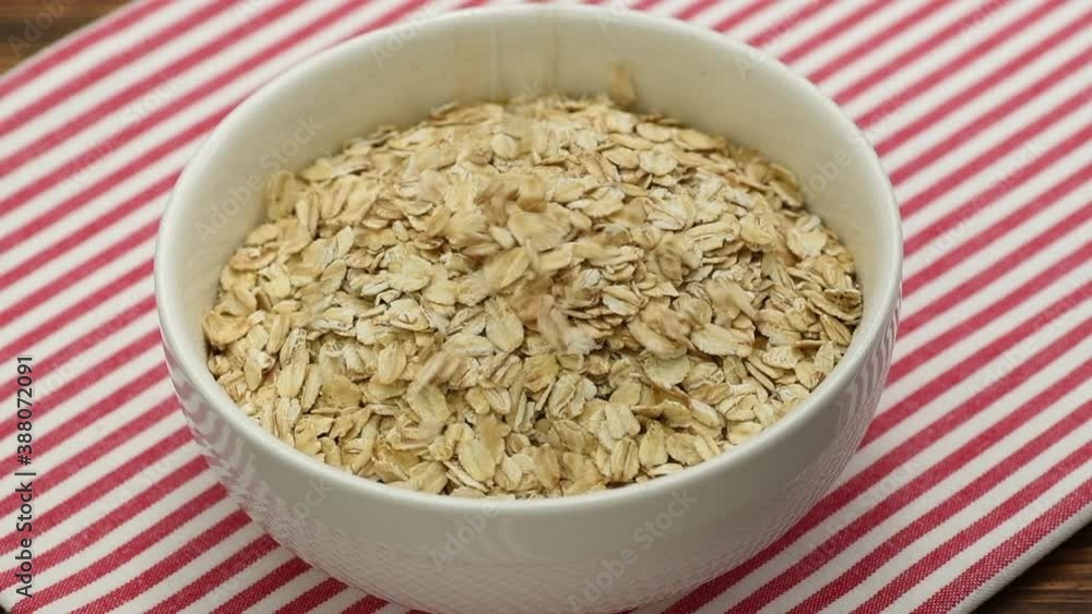 Oat flakes falling into a white bowl, slow motion Oat flakes falling into a white bowl, slow motion