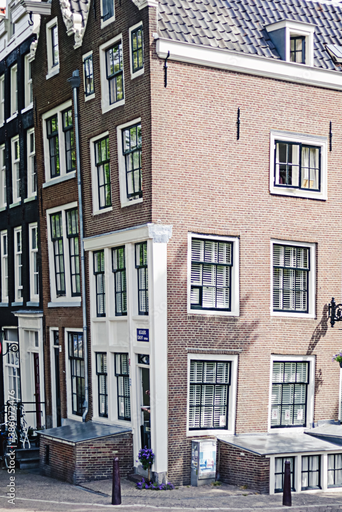 Naklejka premium Amsterdam traditional dancing corner house on a bright summer day. Travel architecture.