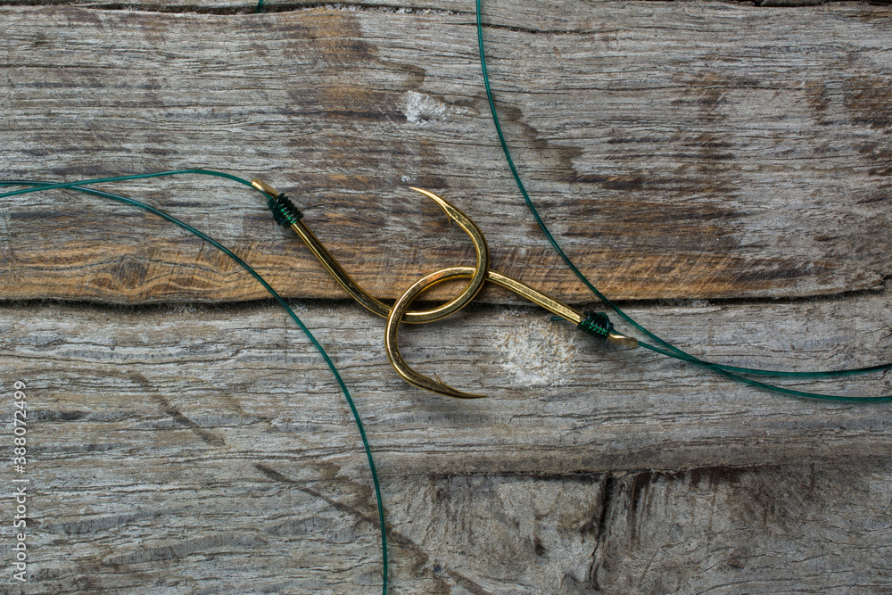 Two fishing hooks tied with fishing line on a wooden background.