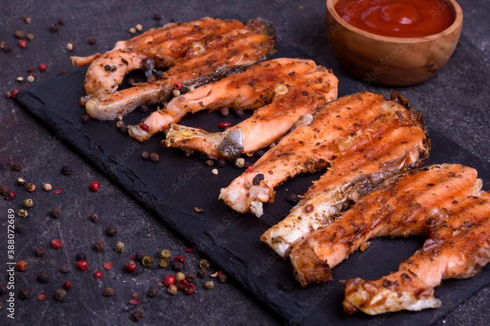Grilled fresh salmon steak with pepper and sause on dark table. Fish for healthy food