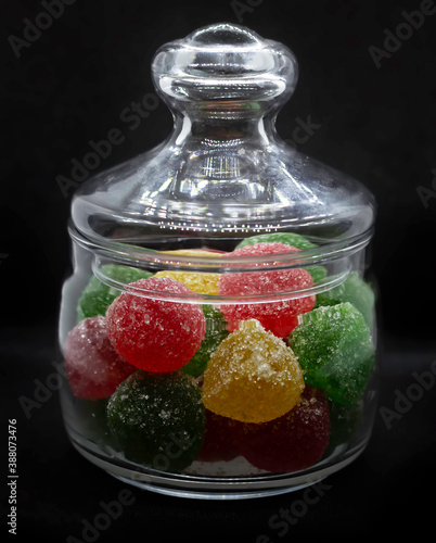 Isolate of multi-colored marmalade in a glass jar on a black background