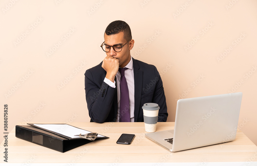 Young business man in his office with a laptop and other documents having doubts Young business man in his office with a laptop and other documents having doubts