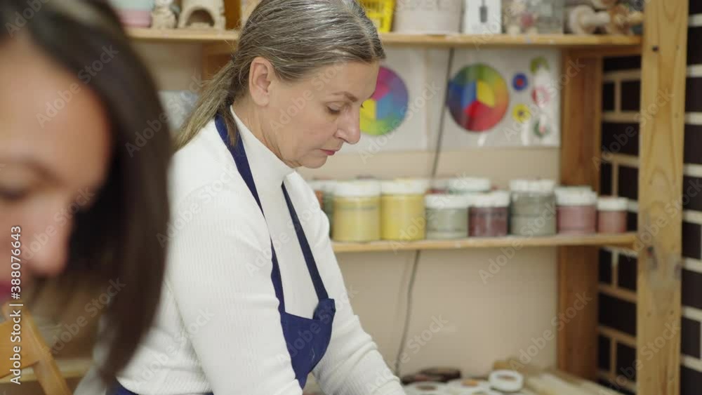Tilt up side view shot of concentrated senior female pottery artist throwing pot on pottery wheel in ceramic art studio Tilt up side view shot of concentrated senior female pottery artist throwing pot on pottery wheel in ceramic art studio