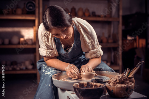 Stylish young lady demonstrates the process of making ceramic dishes using the old technology. Handiwork.