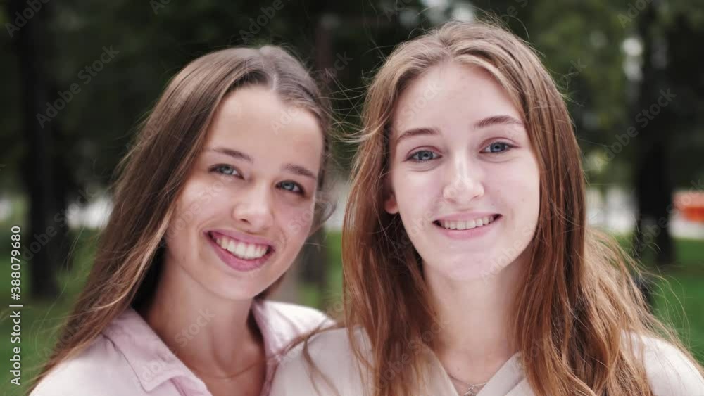 Portrait of two young smiling hipster women friends. Pretty girls, smile and show positive face emotions. Close up portrait. Portrait of two young smiling hipster women friends. Pretty girls, smile and show positive face emotions. Close up portrait.