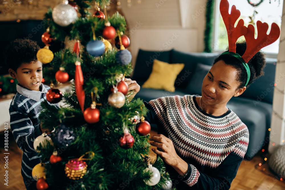 African American mother and son decorating Christmas tree at home. African American mother and son decorating Christmas tree at home.