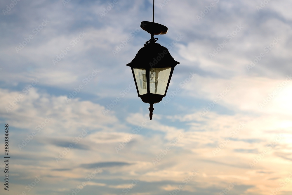 Fototapeta premium Outdoor lantern and cloudy sunset sky. Selective focus.