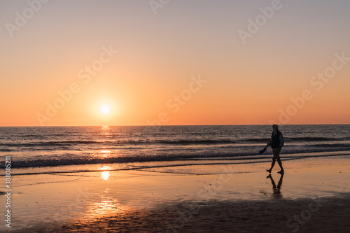 silhouette of a man walking on the beach at sunset