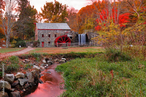 Картината върху платно The Wayside Inn Grist Mill with water wheel and cascade water fall in Autumn at