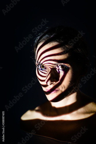 Portrait of a woman illuminated with a projected light in a spiral shape.