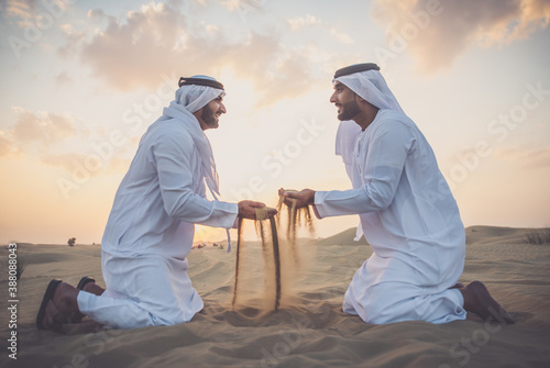 Two business men wearing traditional uae white kandura spending time in the desert of Dubai