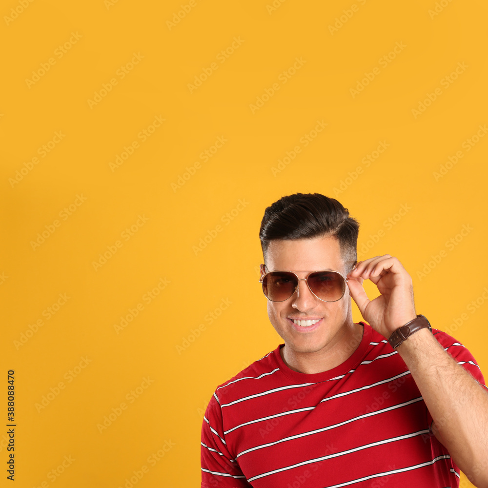 Handsome man wearing sunglasses on yellow background. Space for text Handsome man wearing sunglasses on yellow background. Space for text