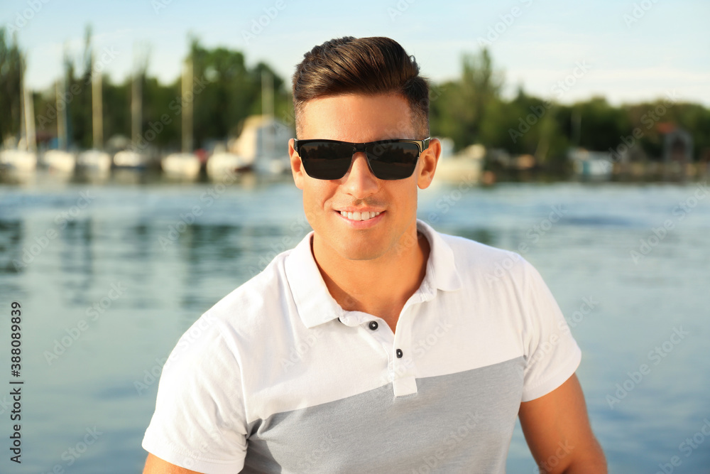 Handsome man wearing stylish sunglasses near river Handsome man wearing stylish sunglasses near river