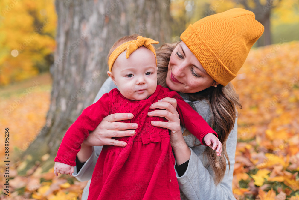 Baby daughter and her mother in the autumn season in park Baby daughter and her mother in the autumn season in park