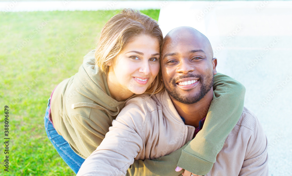 happy group of a multiethnic bald man and a caucasian woman taking a selfie sitting on a bench in a park during autumn holidays. smiling interracial couple of a boy and girl taking self portrait photo happy group of a multiethnic bald man and a caucasian woman taking a selfie sitting on a bench in a park during autumn holidays. smiling interracial couple of a boy and girl taking self portrait photo