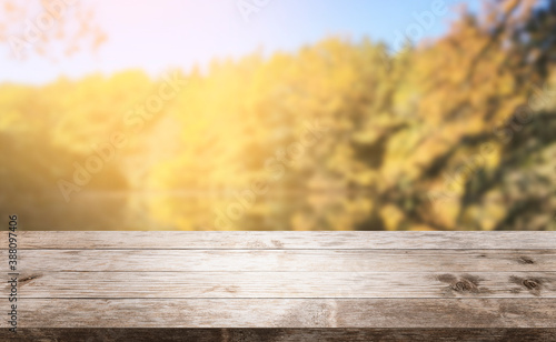 Autumn background, empty old rustic wood table with blur forest trees and sunlight, Autumn fall backdrop, banner for product display advertise online copy space, thanksgiving textured grungy floor.