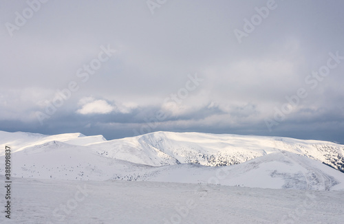 Snow-covered mountain peaks under a cloudy sky.