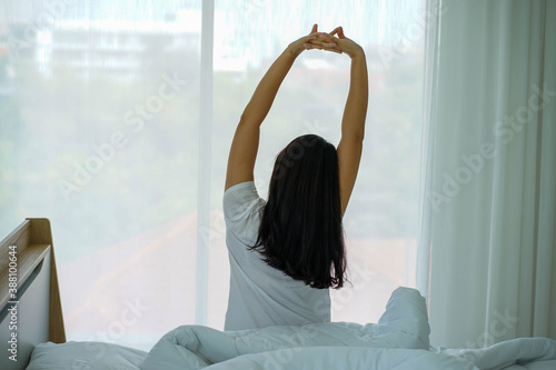 young attrative Asian woman on white pillow and bed sheet in bedroom relaxing on holiday stay home photo