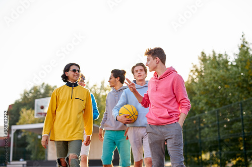 energetic, healthy teens have fun, talk before playing basketball, group of happy teenage boys in colourful casual wear, playing basketball outdoors in the city, go at playground