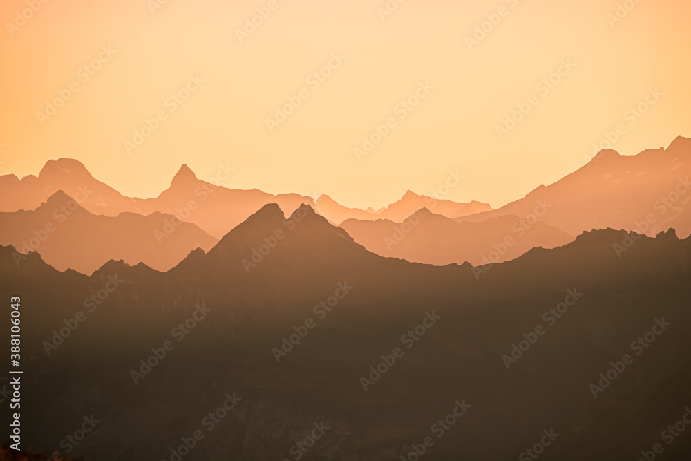 Beautiful Mountain And Sunset at swiss Alps. Dark Silhouette of Mountains on Yellow Sunrise Background