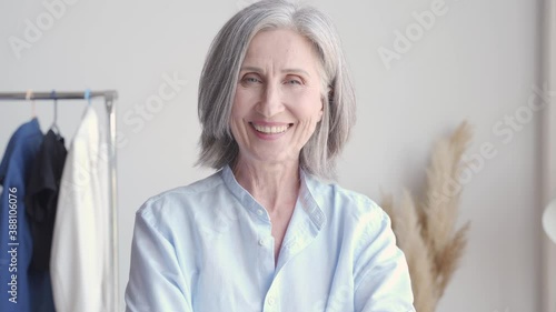 Happy cheerful older stylish small business owner, female fashion designer laughing at workplace, close up headshot portrait. Smiling 60s senior lady dressmaker looking at camera in modern atelier. photo