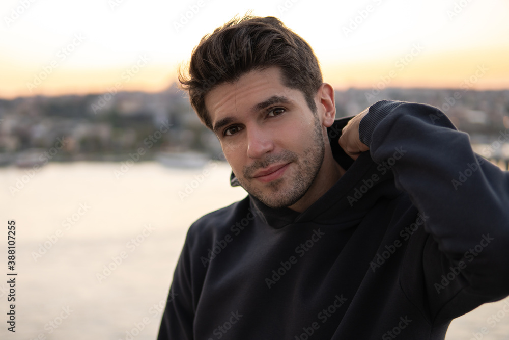 Portrait of a young handsome cute guy fixing his hoodie during the sunset Portrait of a young handsome cute guy fixing his hoodie during the sunset