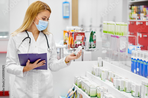 female pharmacist fulfilling a prescription holding drugs in hand, she is checking the script