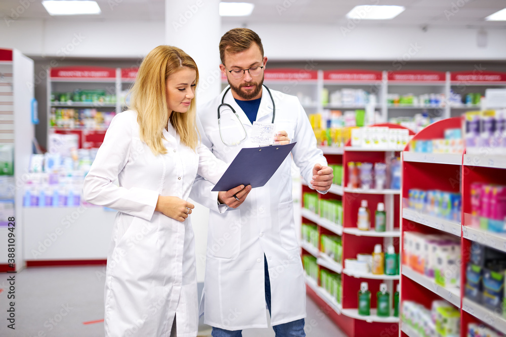 appealing two caucasian pharmacists communicating while supervising medical products, they have talk, checking digital tablet appealing two caucasian pharmacists communicating while supervising medical products, they have talk, checking digital tablet