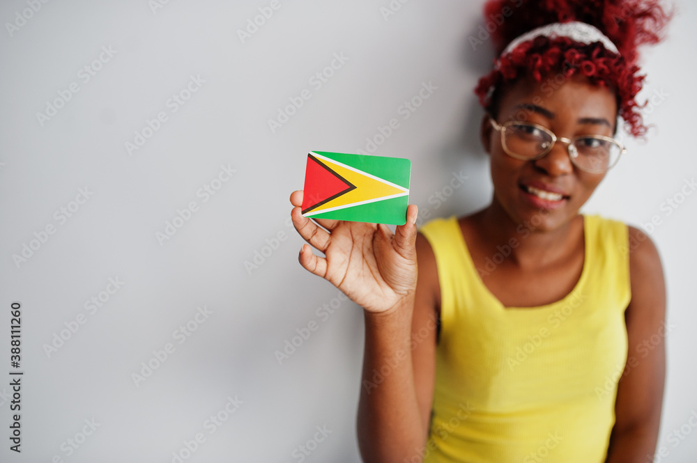 African american woman with afro hair, wear yellow singlet and eyeglasses, hold Guyana flag isolated on white background. African american woman with afro hair, wear yellow singlet and eyeglasses, hold Guyana flag isolated on white background.
