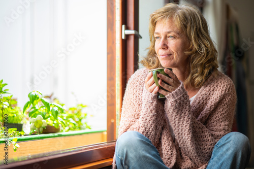 Obraz na płótnie Adult woman taking tea pensive looking out the window