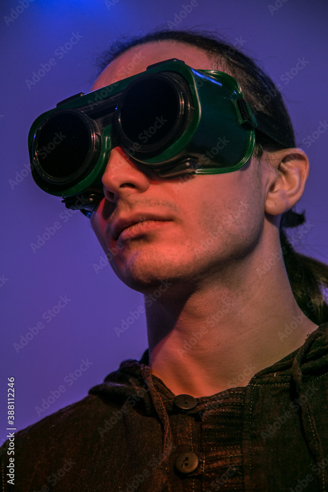 A man in welding glasses on purple background A man in welding glasses on purple background