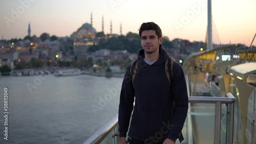 Handsome young tourist man walking in the slow-motion in front of the Historic Mosque in Istanbul, Turkey during the sunset 